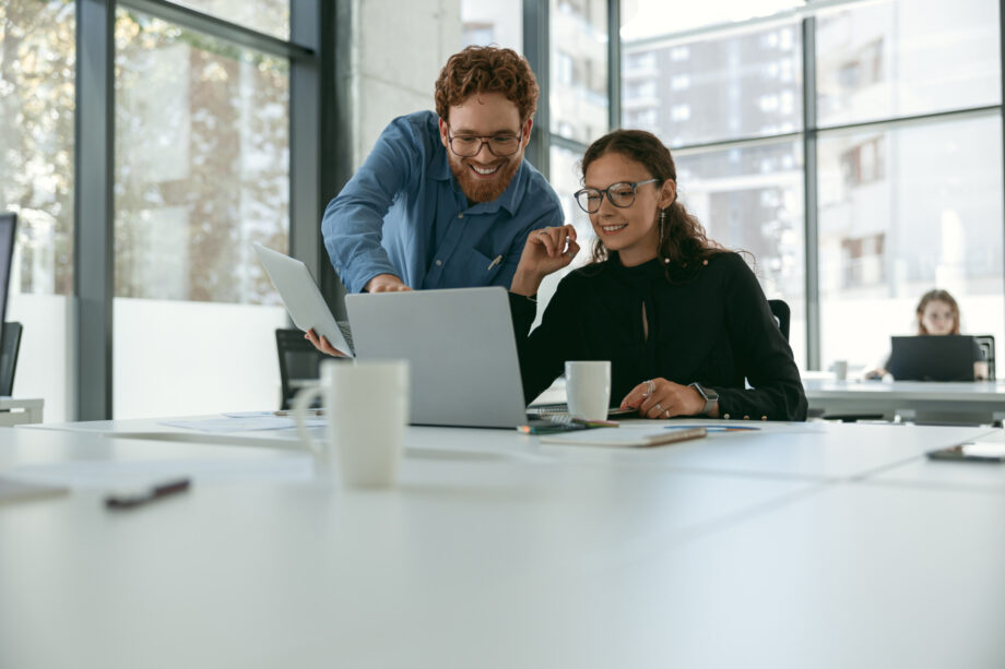 Two business colleagues disscuss biz issue while use laptop standing in office. High quality photo