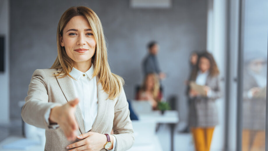 Happy office employee giving hand for shaking . Arm of business woman offering handshake. Professional welcoming colleague or new partner. HR manager hiring greeting at job interview. Close up shot