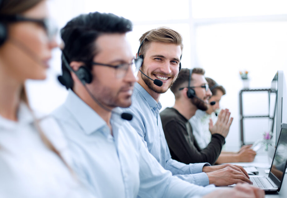 Young handsome male customer support phone operator with headset working in call center.