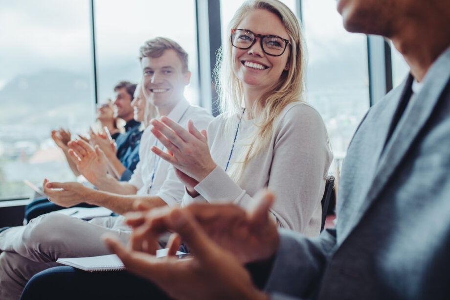 Group of businesspeople sitting at seminar clapping hands. Businessmen and businesswomen applauding after a successful presentation at a conference.